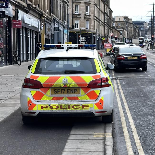 Police patrol car parked on cycleway next to a double yellow line. Vacant parking space visible in the background.