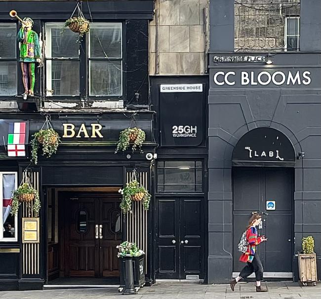 Colourfully dressed person walking past C.C. Blooms.