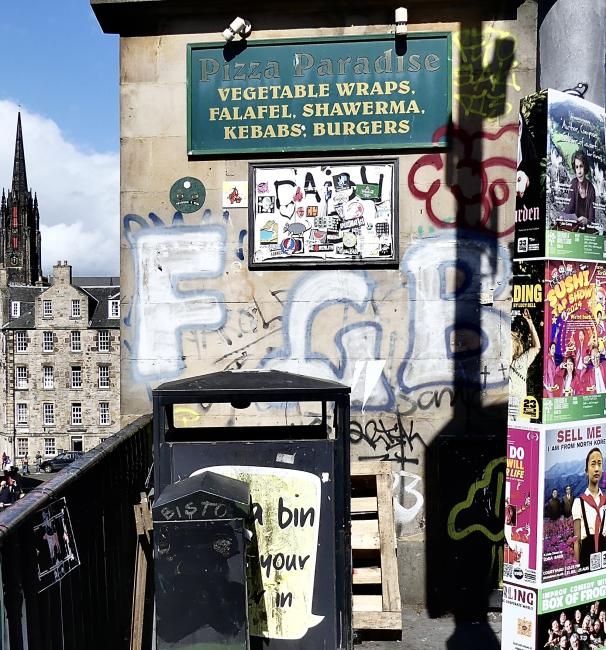 Complicated Festival-time street scene involving varied architecture, graffiti and signage.